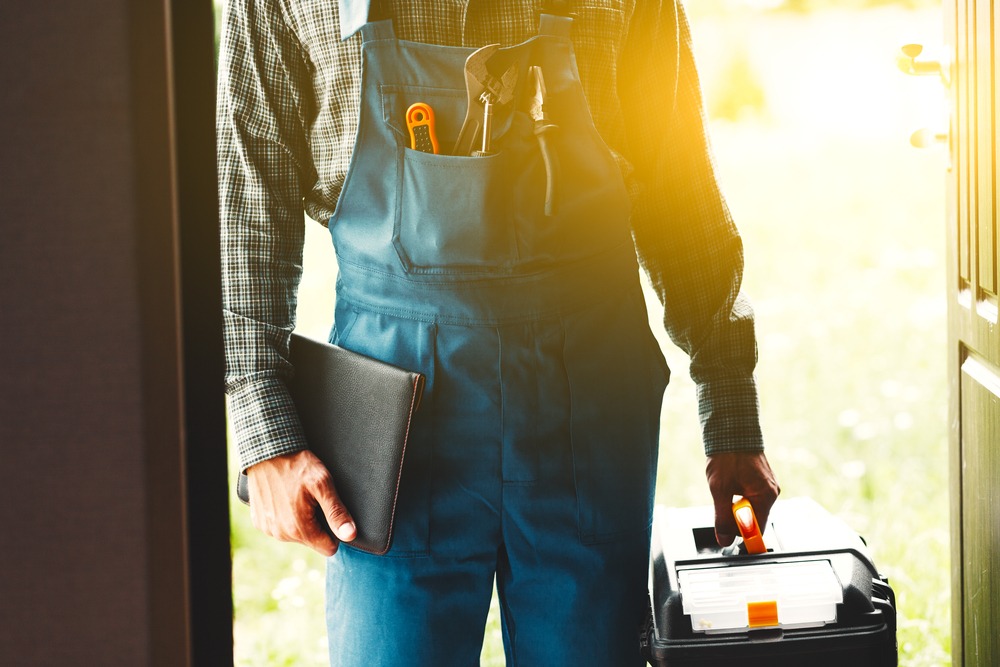 A man in overalls holding a tool box